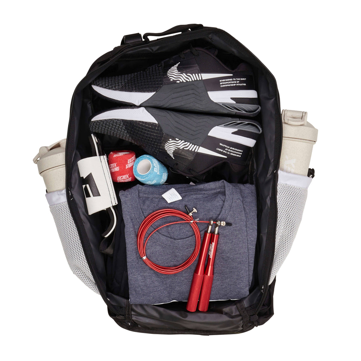 Mochila aberta V2 com equipamento de treino e duas garrafas nos bolsos laterais.